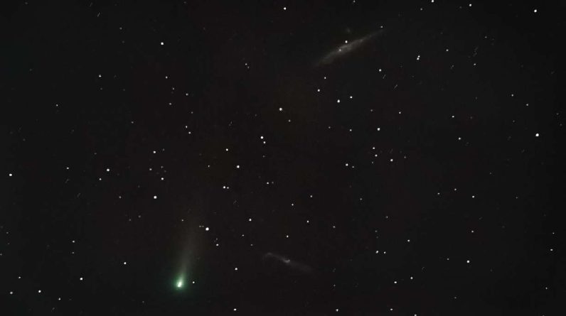 An undated photo of Comet Leonard in the night sky accompanied by two galaxies.