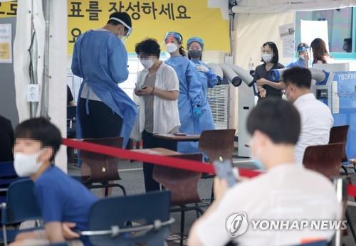 La foto, tomada el 22 de julio de 2022, muestra a ciudadanos esperando en fila para ser examinados de COVID-19, en una clínica provisional en Gangnam, en el sur de Seúl.
